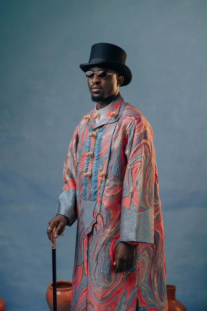 Man in patterned Niger Delta attire with a black hat and coral-coloured accessories