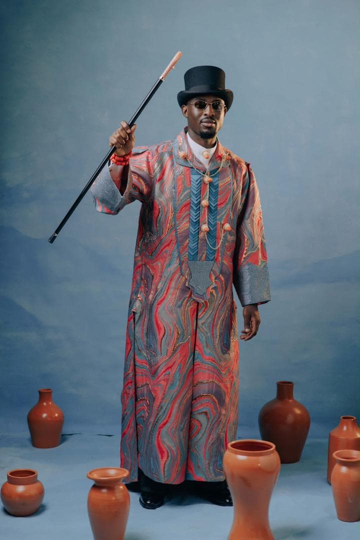 Man in patterned Niger Delta ceremonial dress with a top hat and walking cane